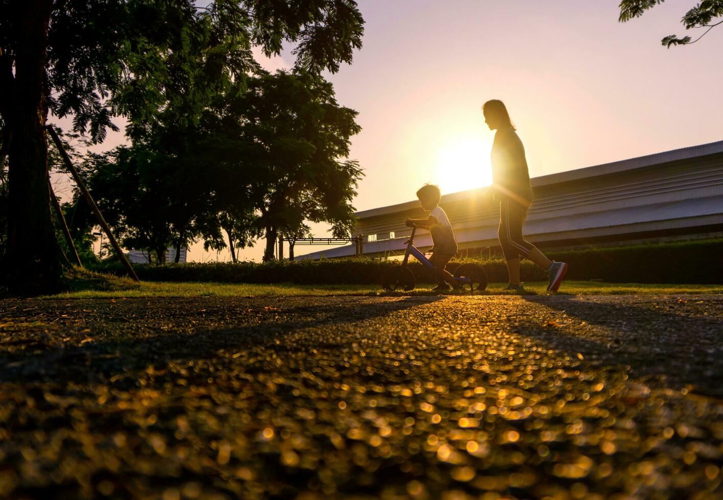 asiático madre ayuda su hijo paseo un bicicleta foto