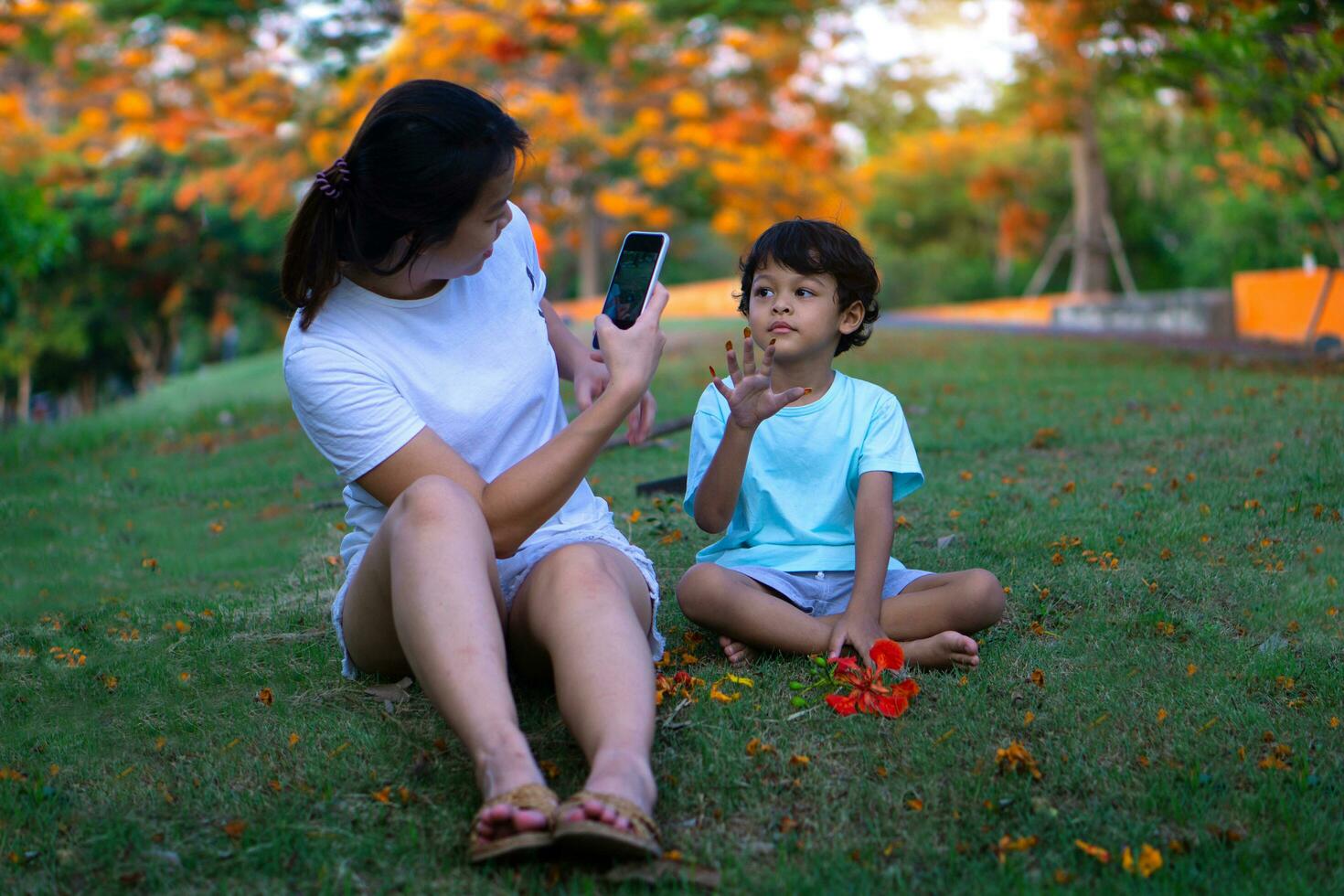 Asian mother and son sitting in the park photo