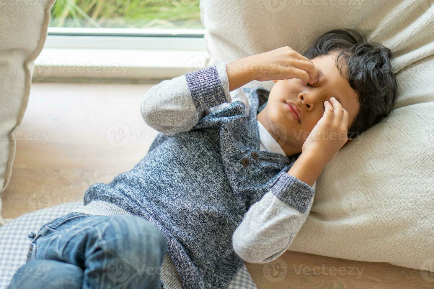 An Asian boy has eyestrain due to excessive playing with mobile phones. photo