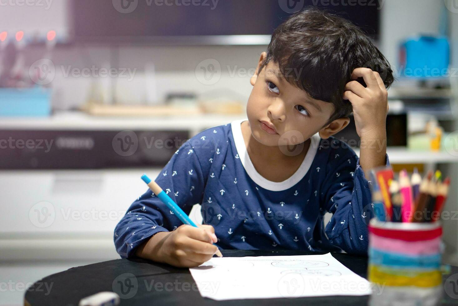 Boy doing homework or work sheet before bedtime. photo