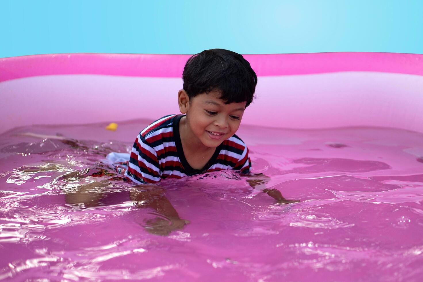 asiático chico jugando en un niño caucho piscina foto