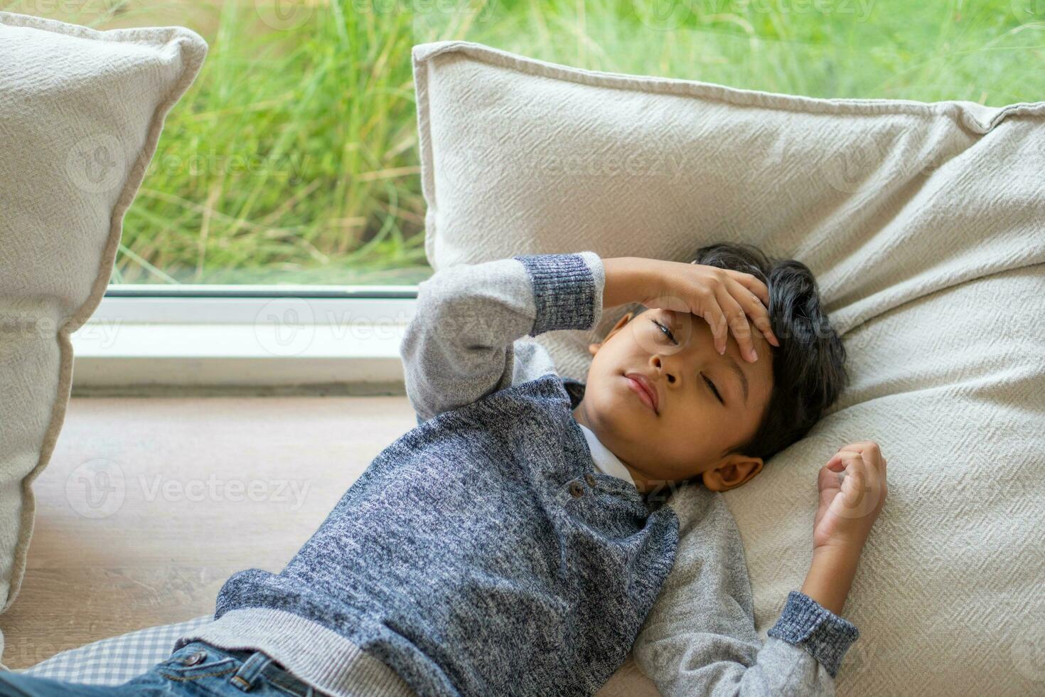 An Asian kid is suffering from a headache photo