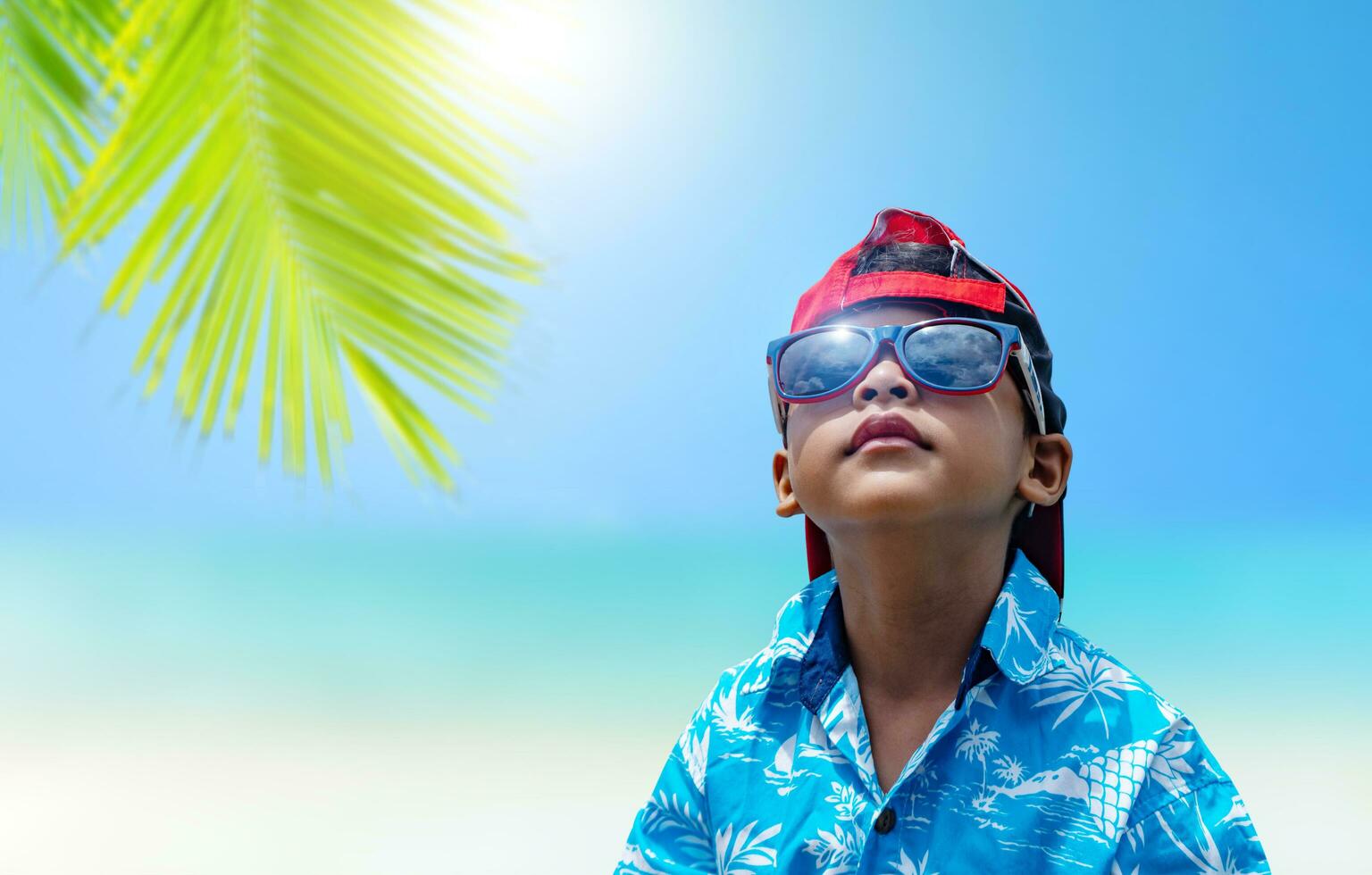 Asian boys wear sunglasses and summer clothes on a bright summer sea background. photo