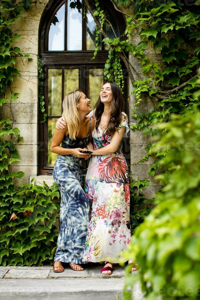 Pretty young women using mobile phone by the old house with ivy photo