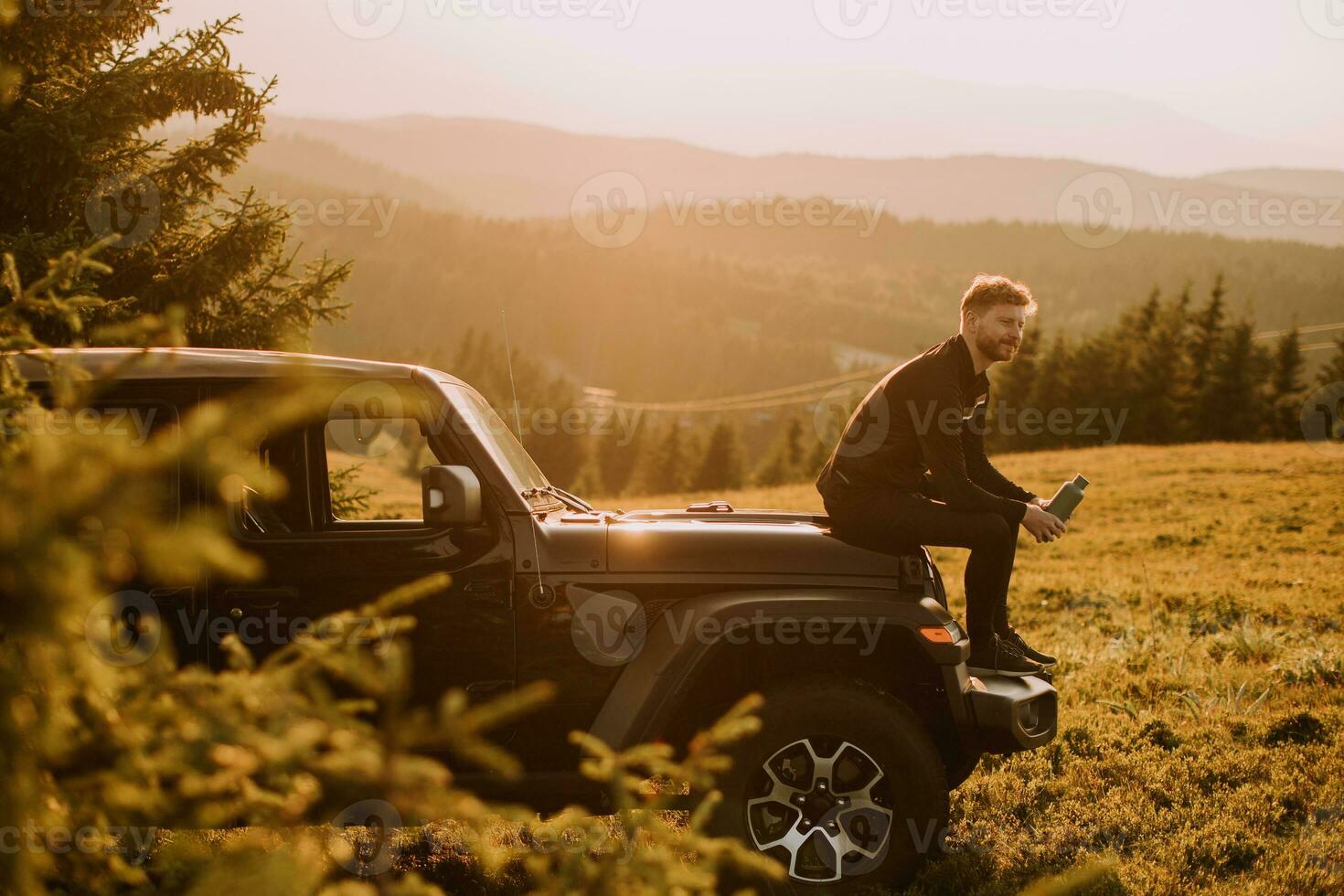 Young man relaxing on a terrain vehicle hood at countryside photo