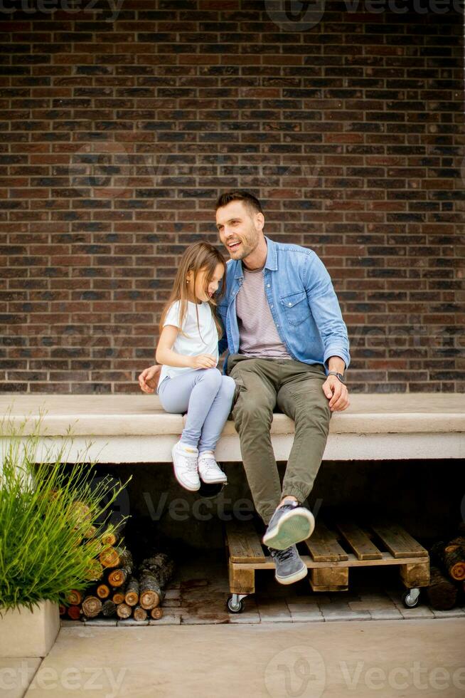 padre y su hija tener un bueno hora en frente de casa puerta foto