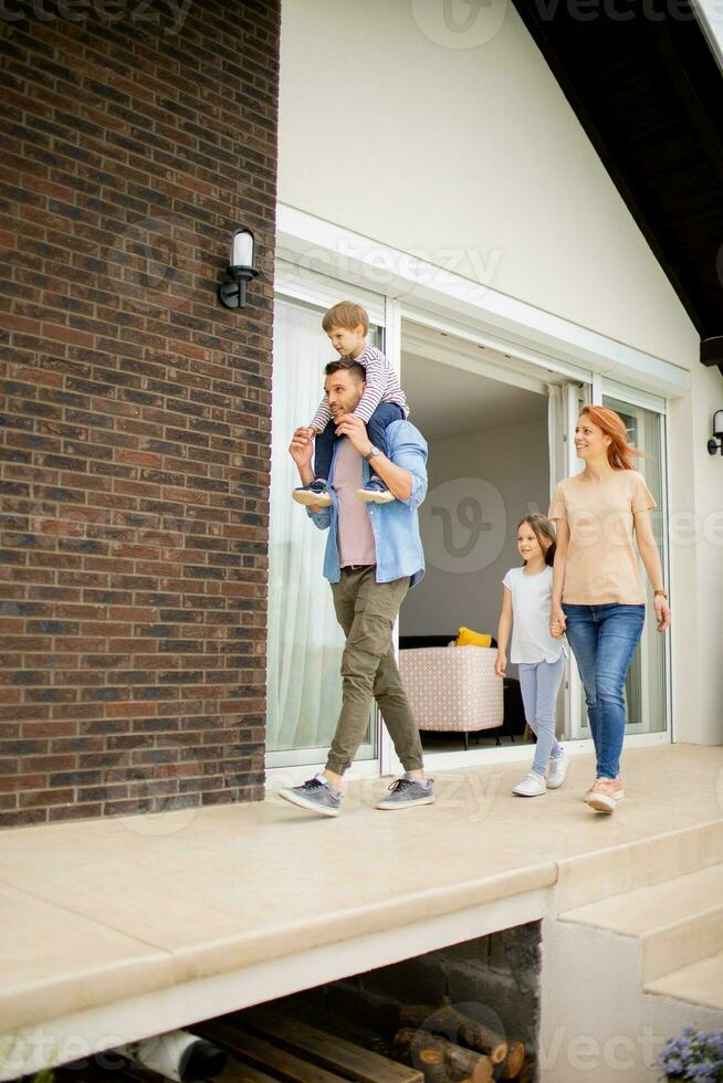 Family with a mother, father, son and daughter walking by the wall of brick house photo
