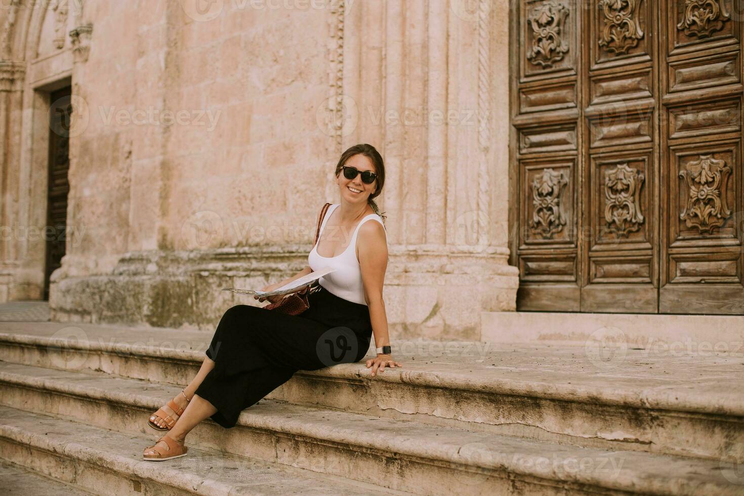 Female tourist with city map by the church San Francesco dAssisi in Ostuni, Italy photo