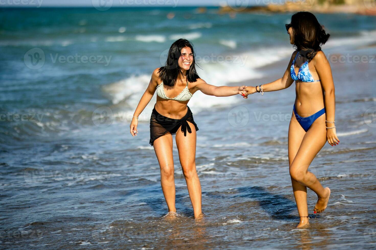 Two pretty young woman having fun on the seaside photo