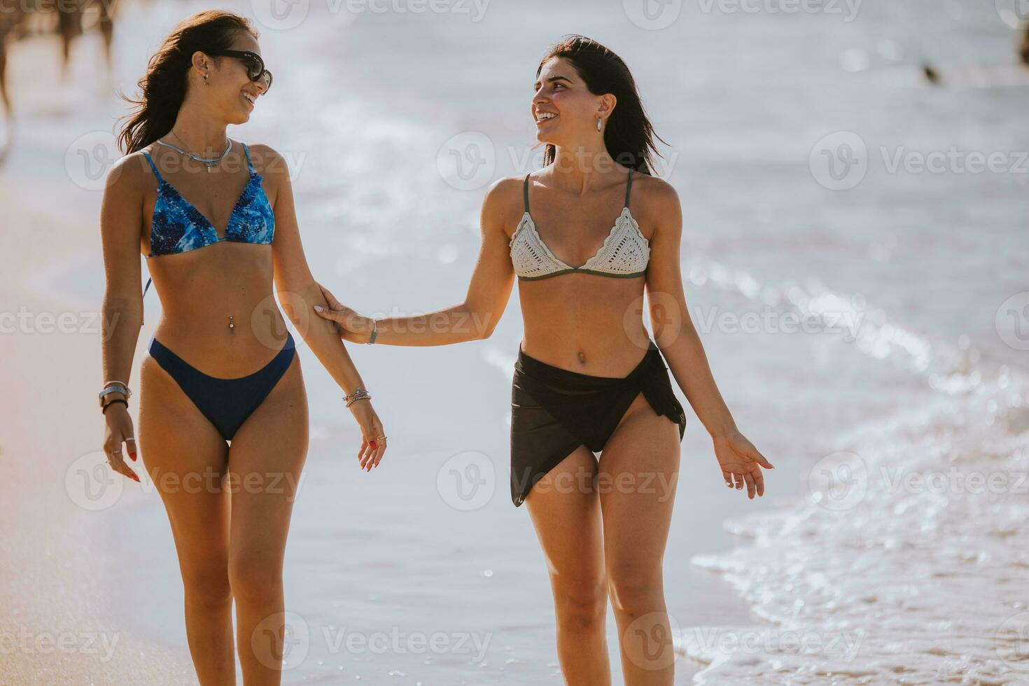 dos bonito joven mujer teniendo divertido en el playa foto