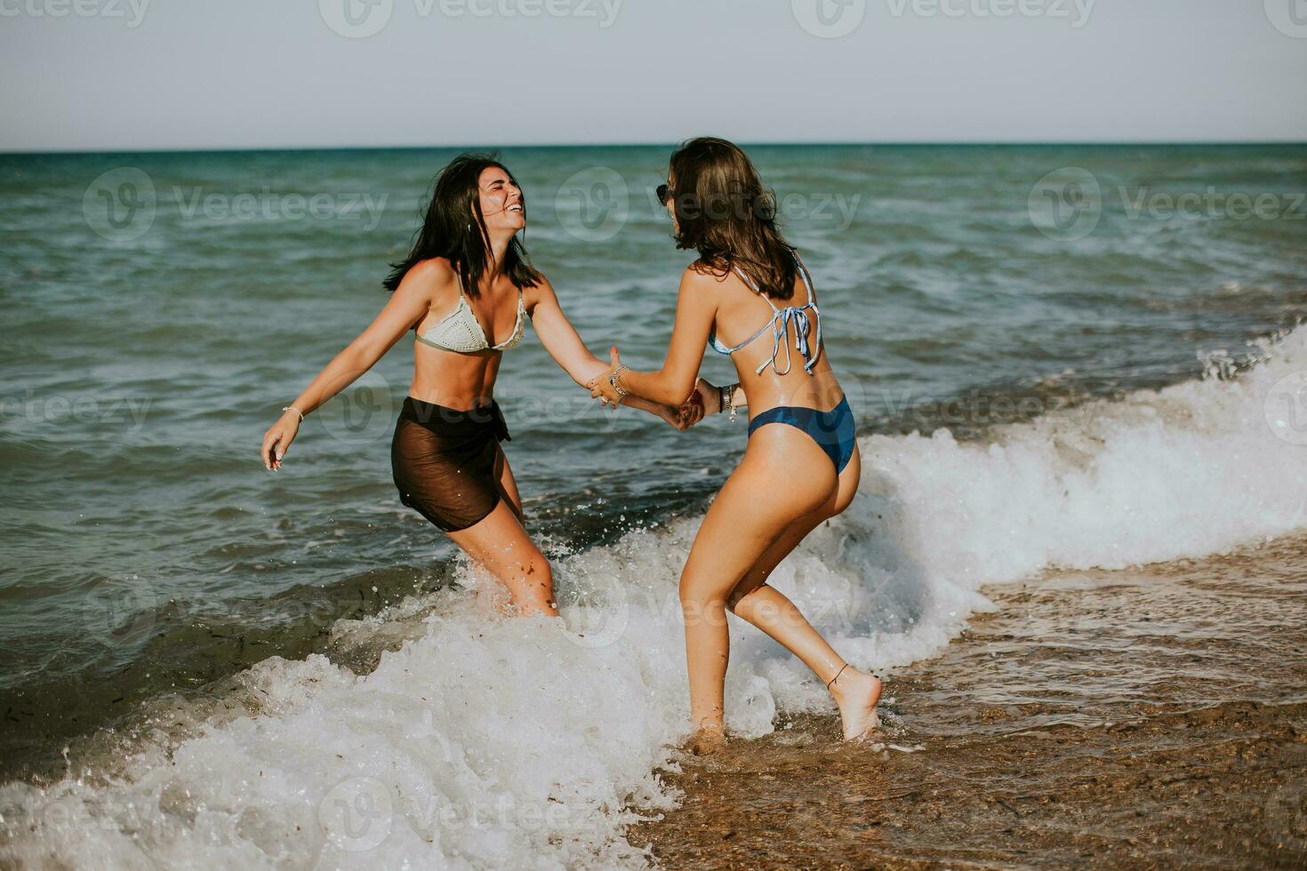 Two pretty young woman having fun on the seaside photo