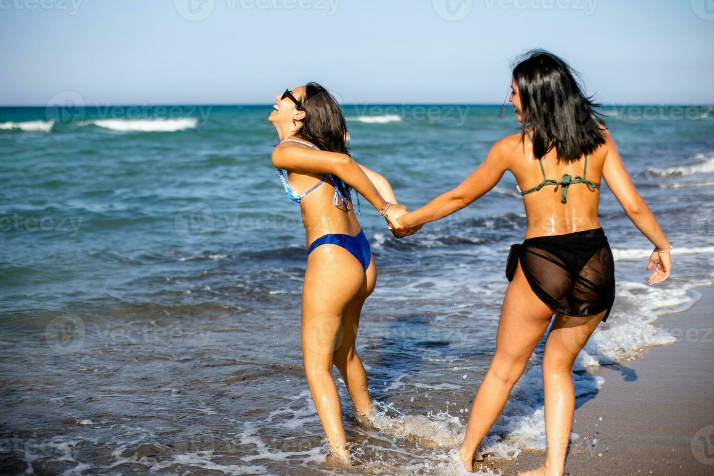 Two pretty young woman having fun on the seaside photo