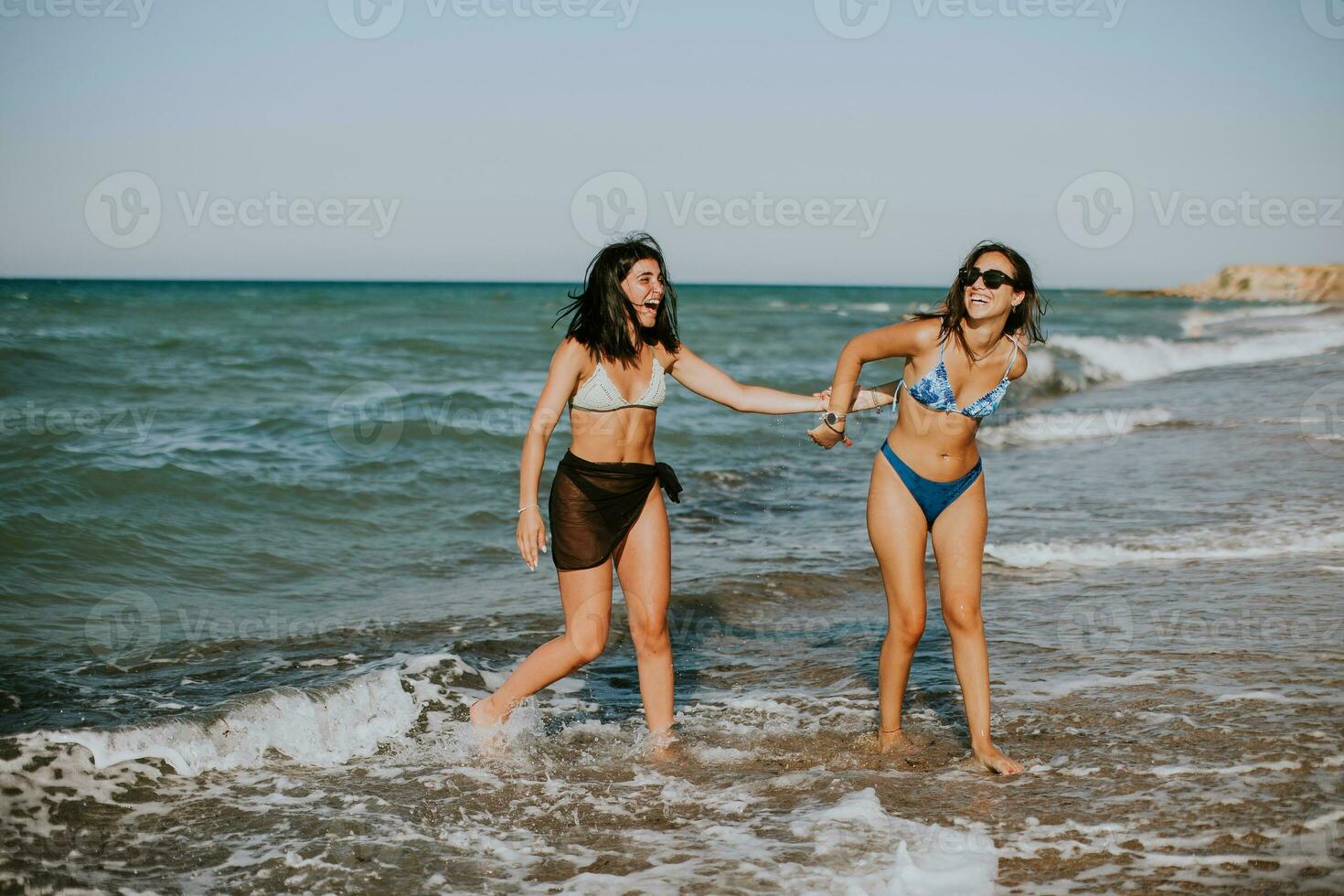 Two pretty young woman having fun on the seaside photo