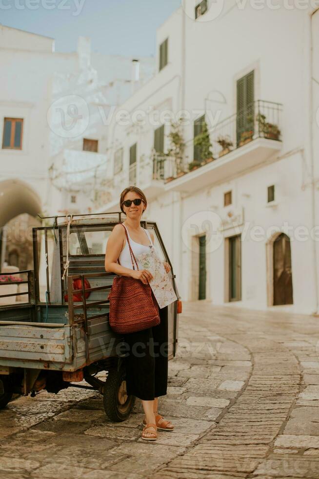 Female tourist with paper city map on narrow streets of Ostuni, Italy photo