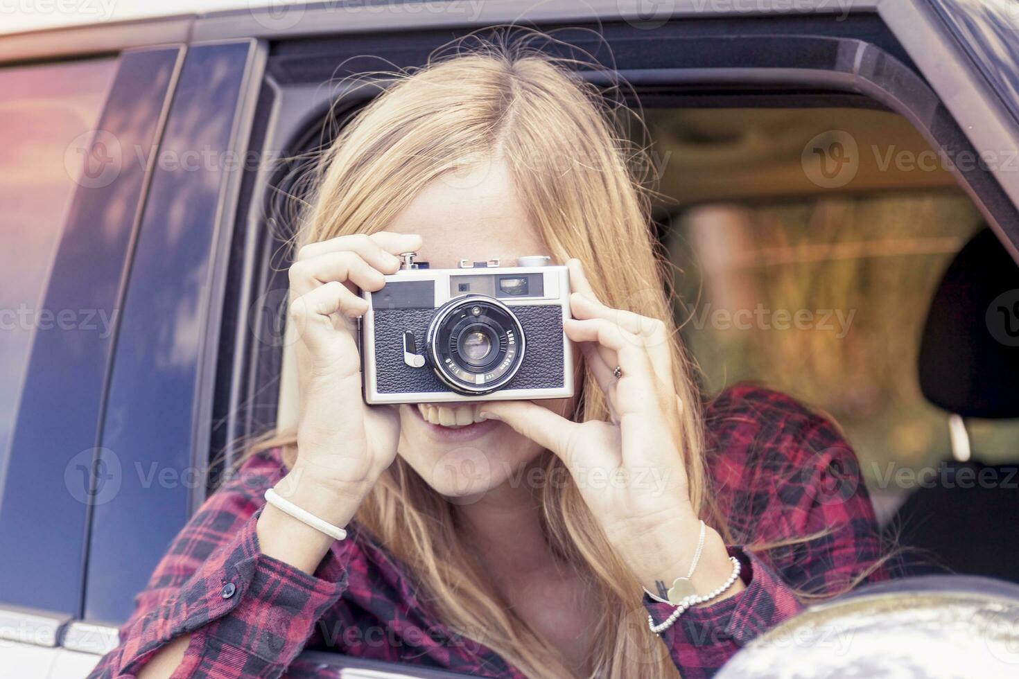 young blond girl takes a photo from a car