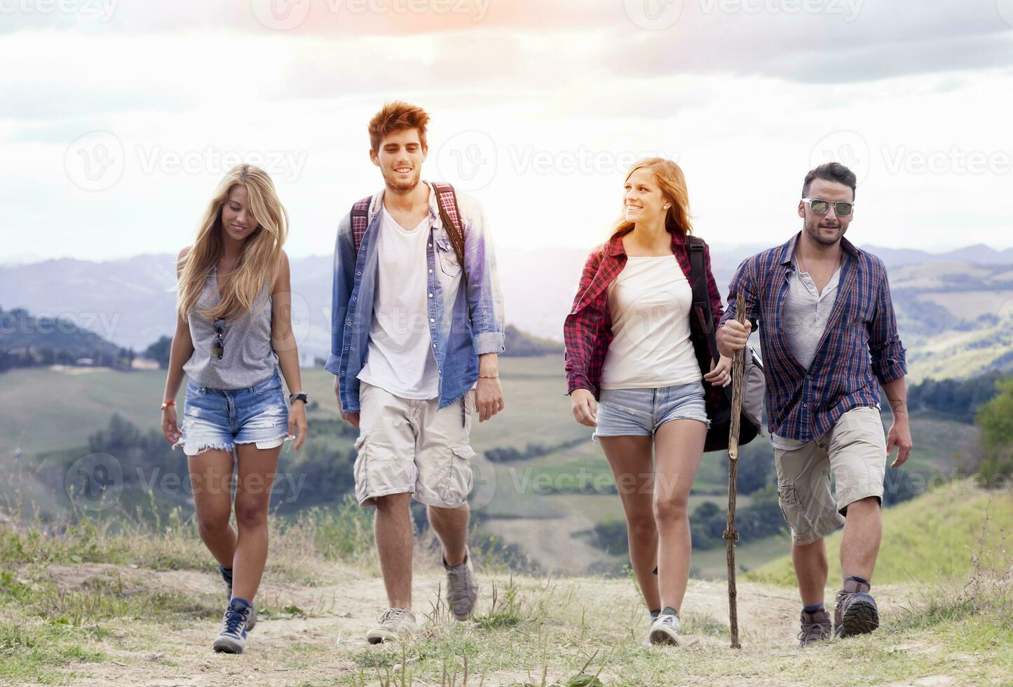 group of young hikers walking toward the horizon over the mountain photo