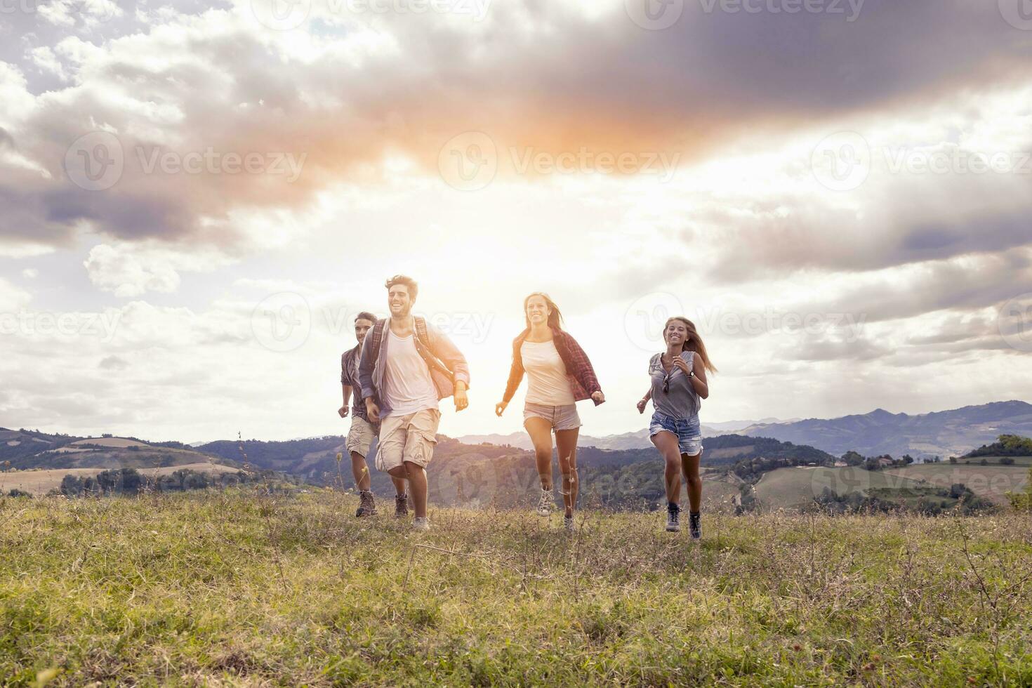 group of young hikers running toward the horizon over the mountain photo