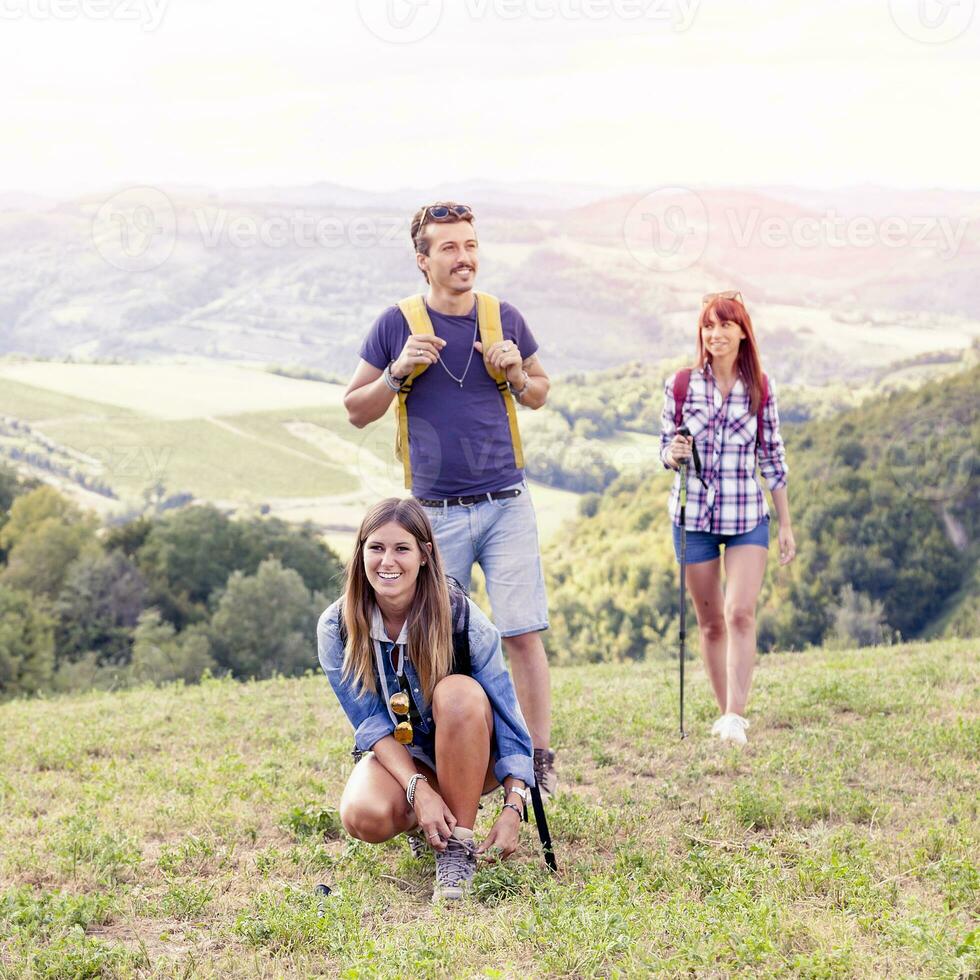 group of young hikers walking toward the horizon over the mountain photo