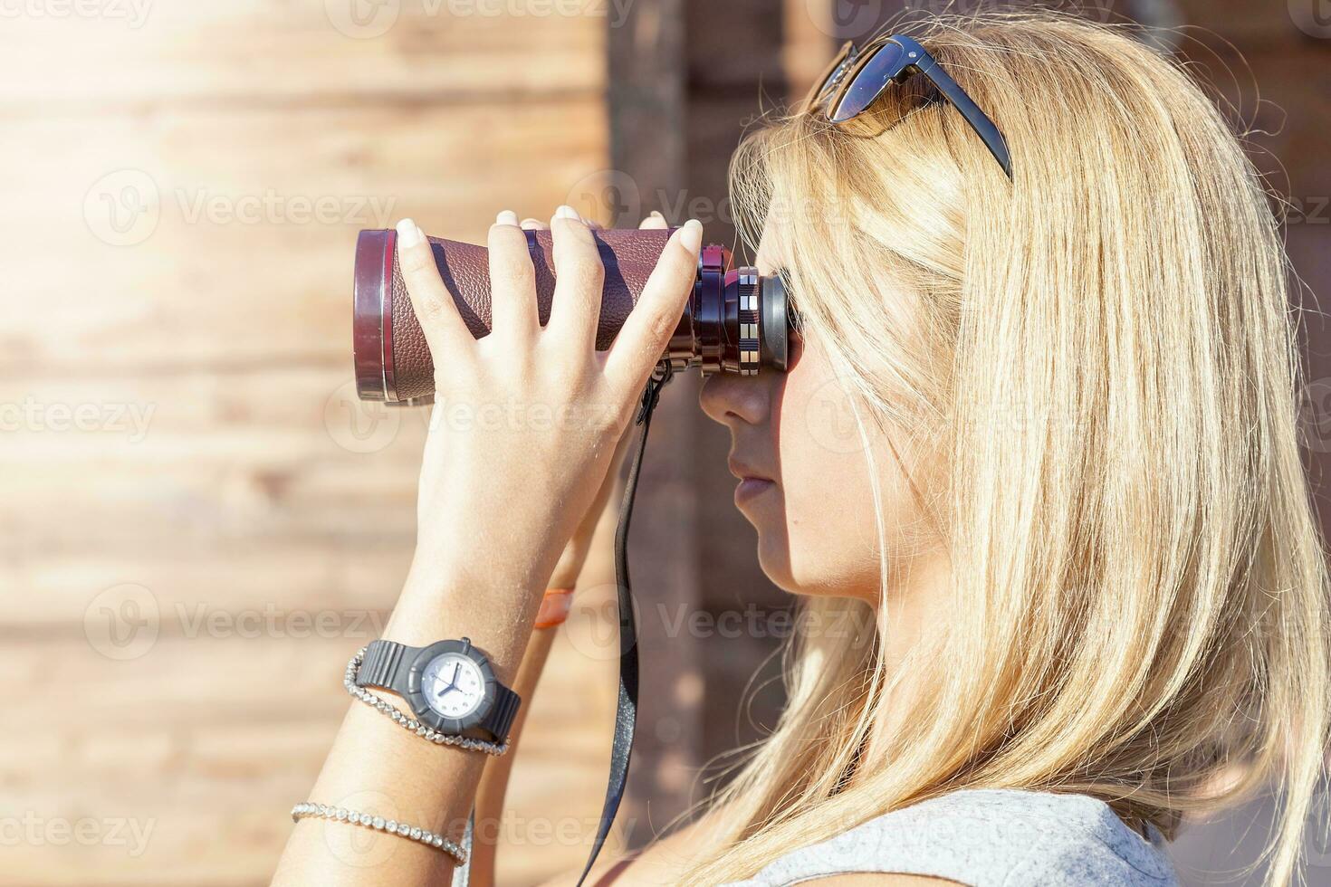 pretty girl with binoculars looking at the horizon photo