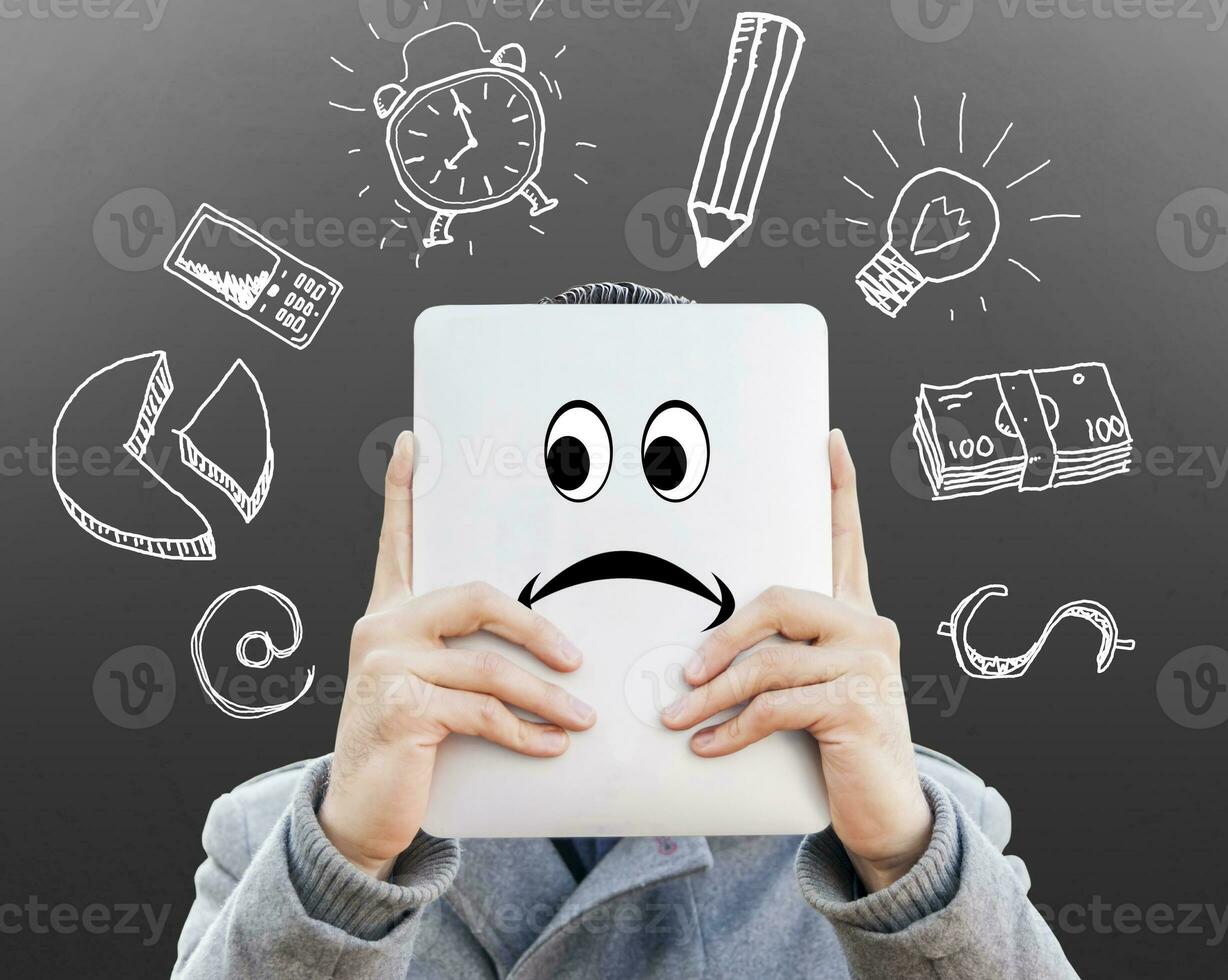 young businessman with tablet in front of his face surrounded of sketches symbols on the wall photo