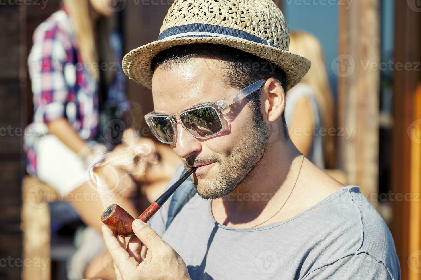 young hiker lights his pipe in front of the hut photo