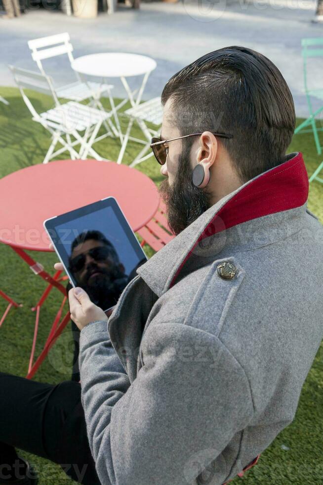 young hipster consults his laptop sitting at bar photo