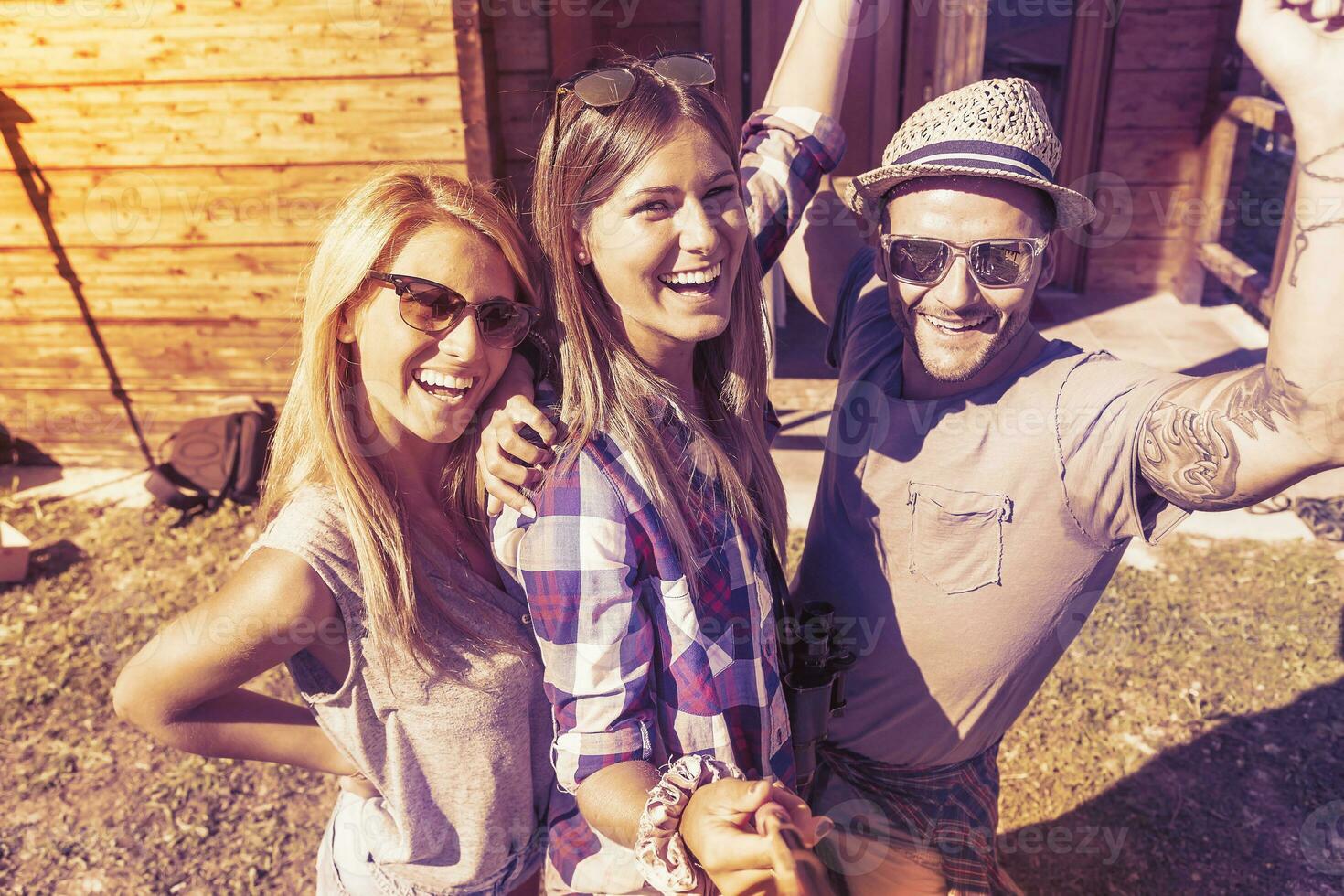 group of smiling friends taking funny selfie with smart phone photo