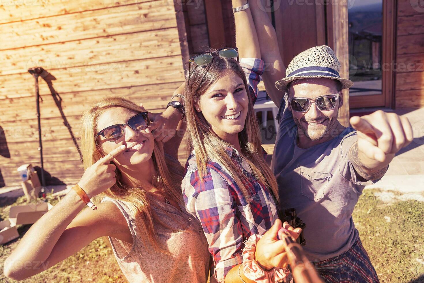 group of smiling friends taking funny selfie with smart phone photo