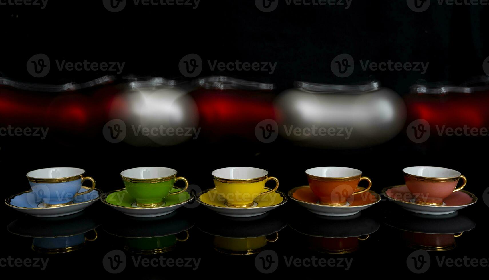 moving blurry christmas balls over colorful cups on black background photo