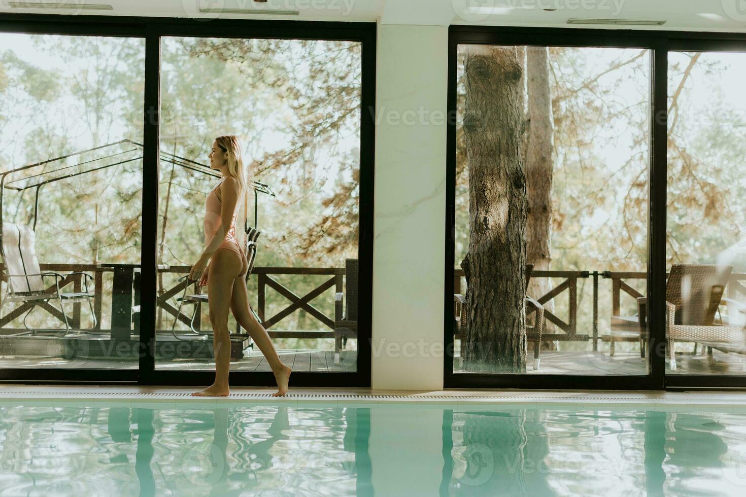 Young woman walking by the indoor swimming pool photo