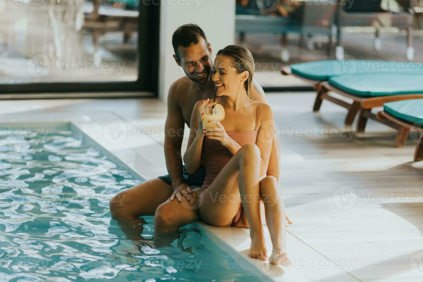 Young couple relaxing by the indoor swimming pool photo