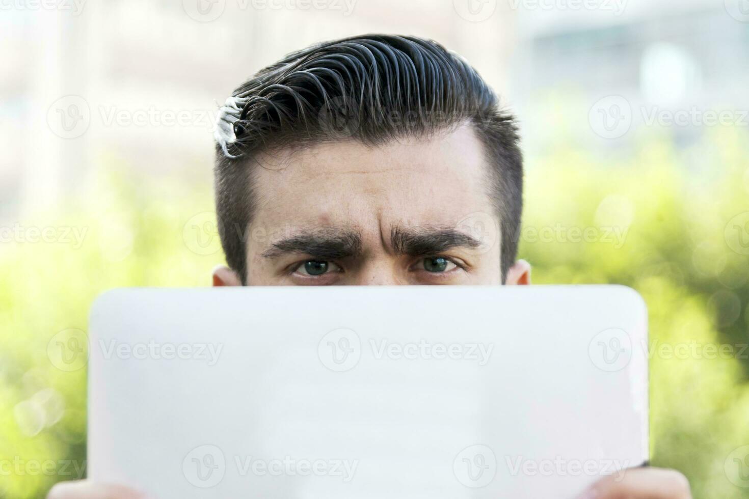young hipster businessman holding the laptop in front of face photo