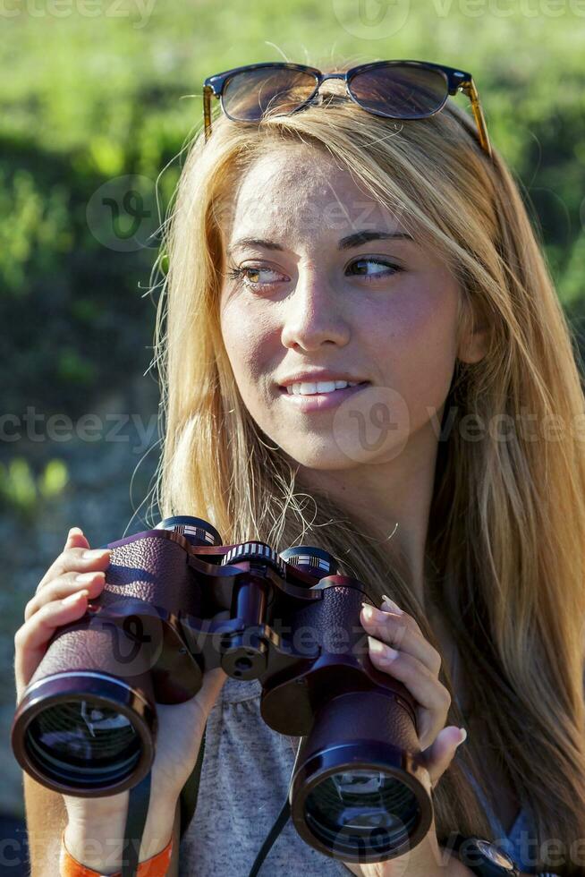 pretty girl with binoculars looking at the horizon photo