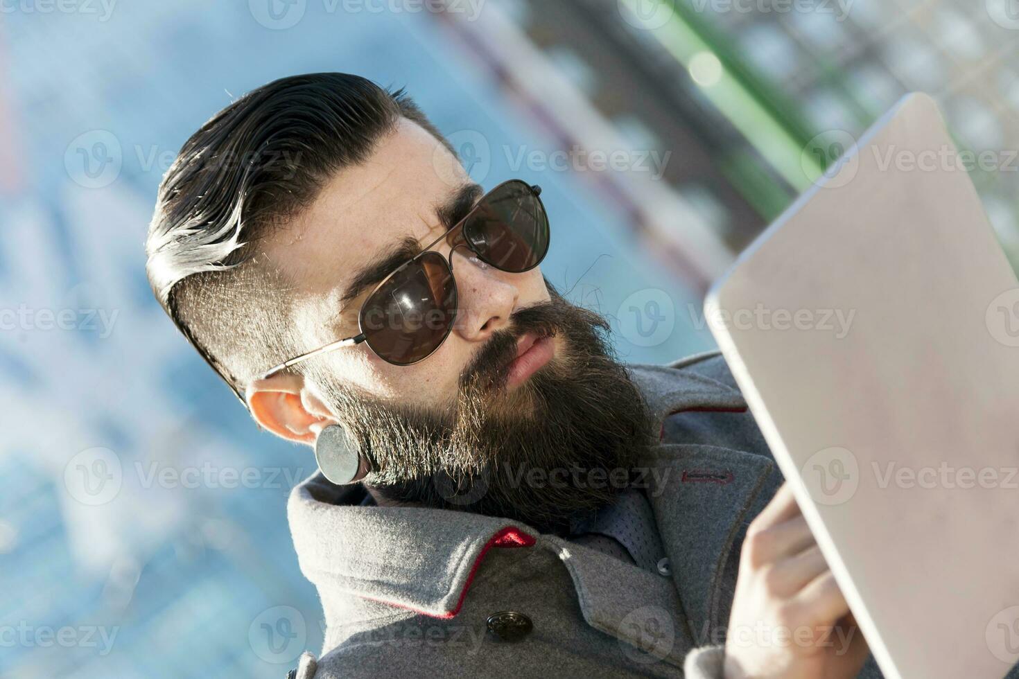 young hipster businessman consults his laptop in the heart of city photo