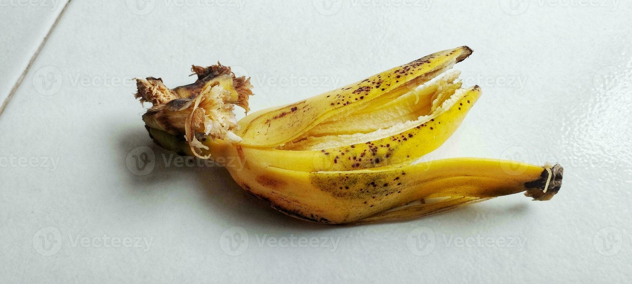 A ripe banana peel lies on the white floor photo