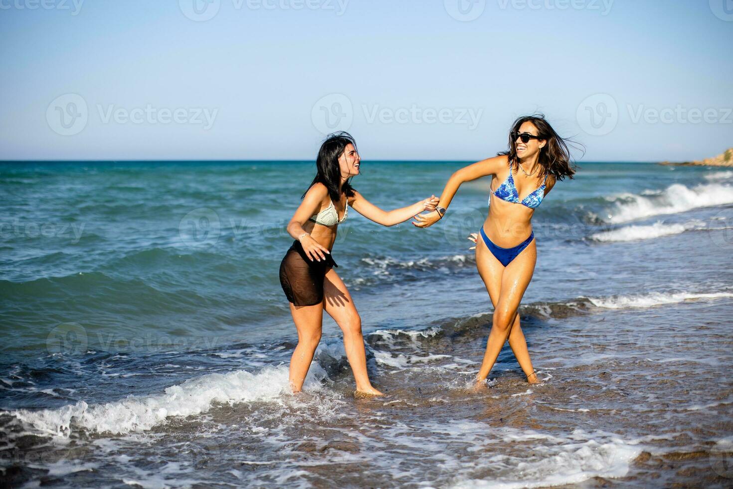 dos bonito joven mujer teniendo divertido en el playa foto