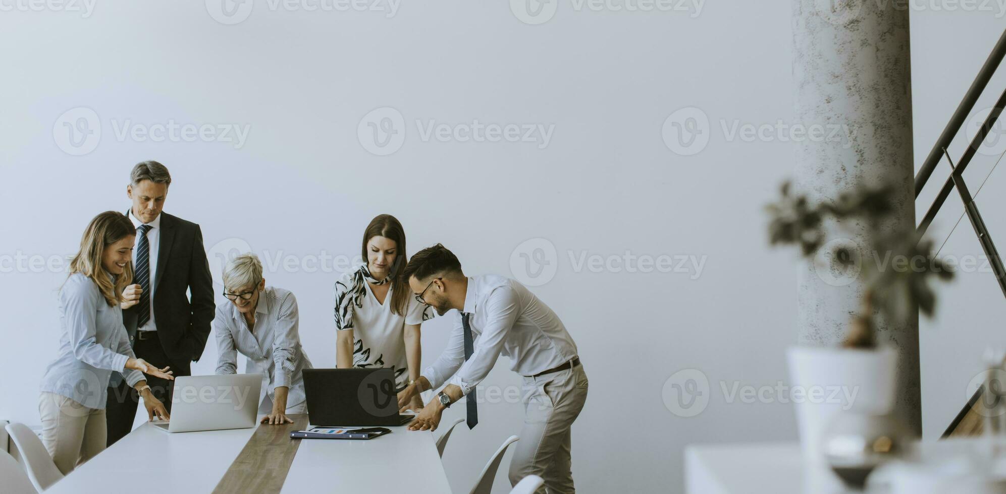 Group of business people with young adults and senior woman colleague on meeting at modern bright office interior photo