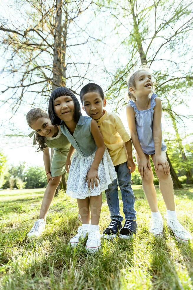 grupo de niños asiáticos y caucásicos divirtiéndose en el parque foto