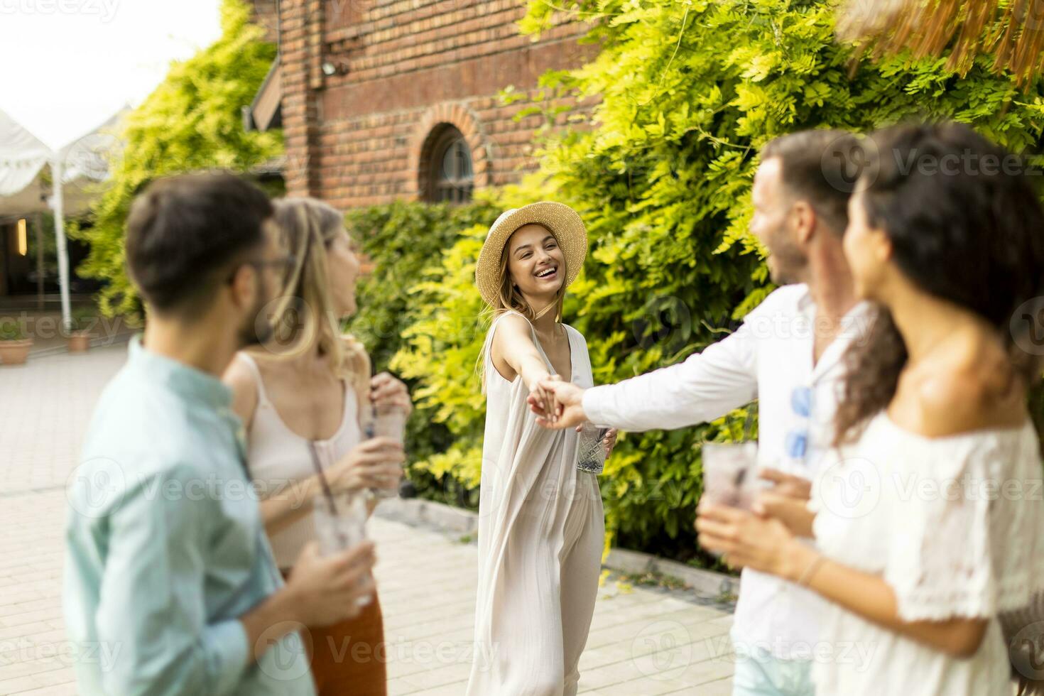 Group of young people cheering and having fun outdoors with drinks photo