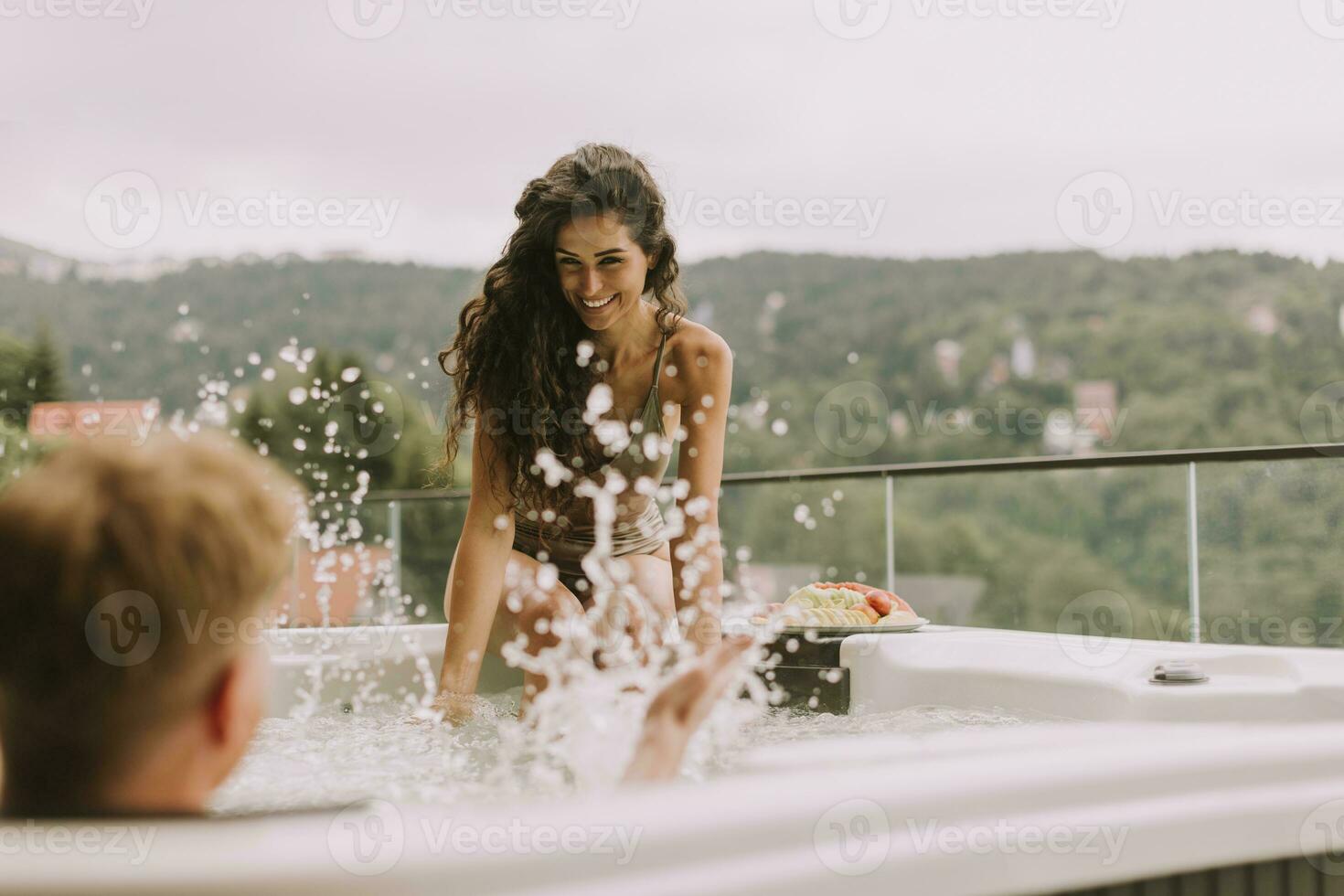 Young couple enjoying in outdoor hot tub on vacation photo