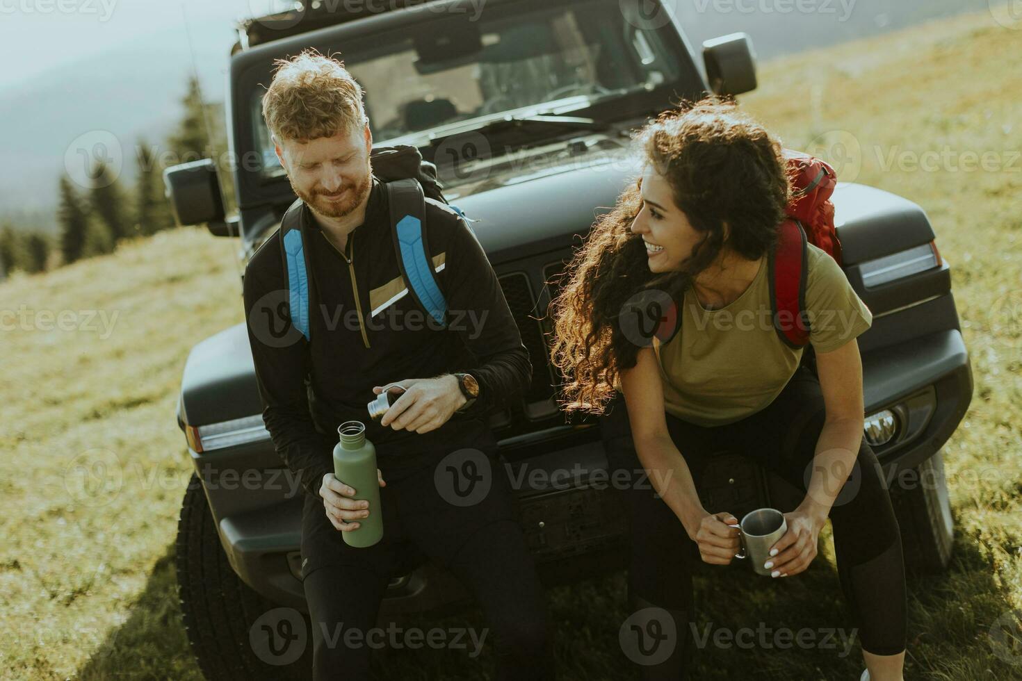 Young couple relaxing on a terrain vehicle hood at countryside photo