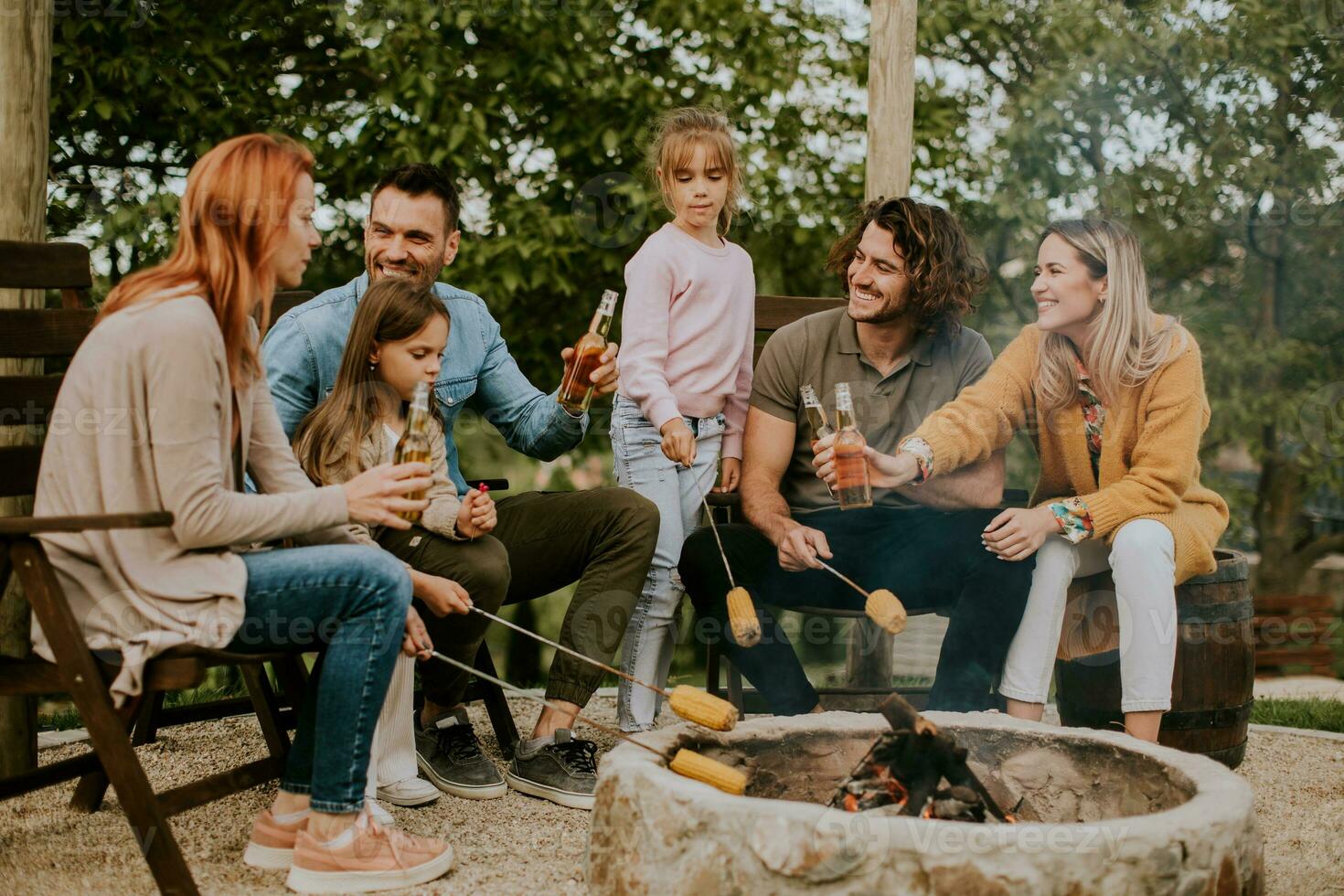 Friends having good time and baking corns in the house backyard photo