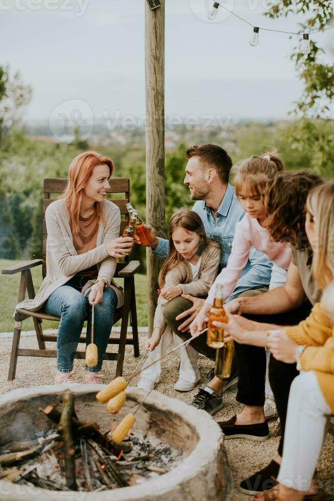 Friends having good time and baking corns in the house backyard photo