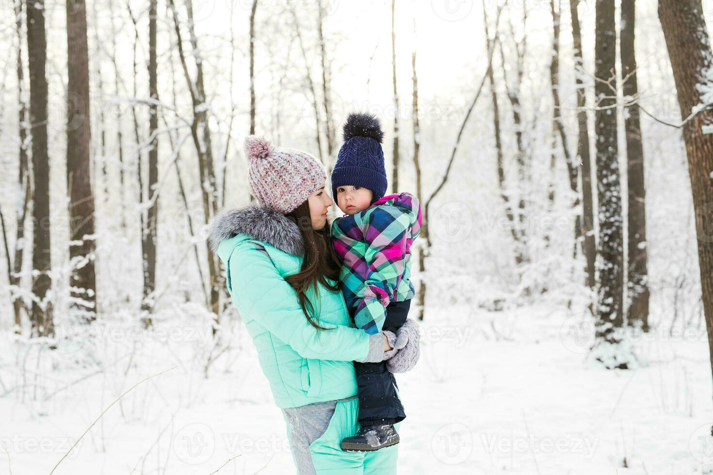 happy family mother and child baby daughter on a winter walk in the woods photo