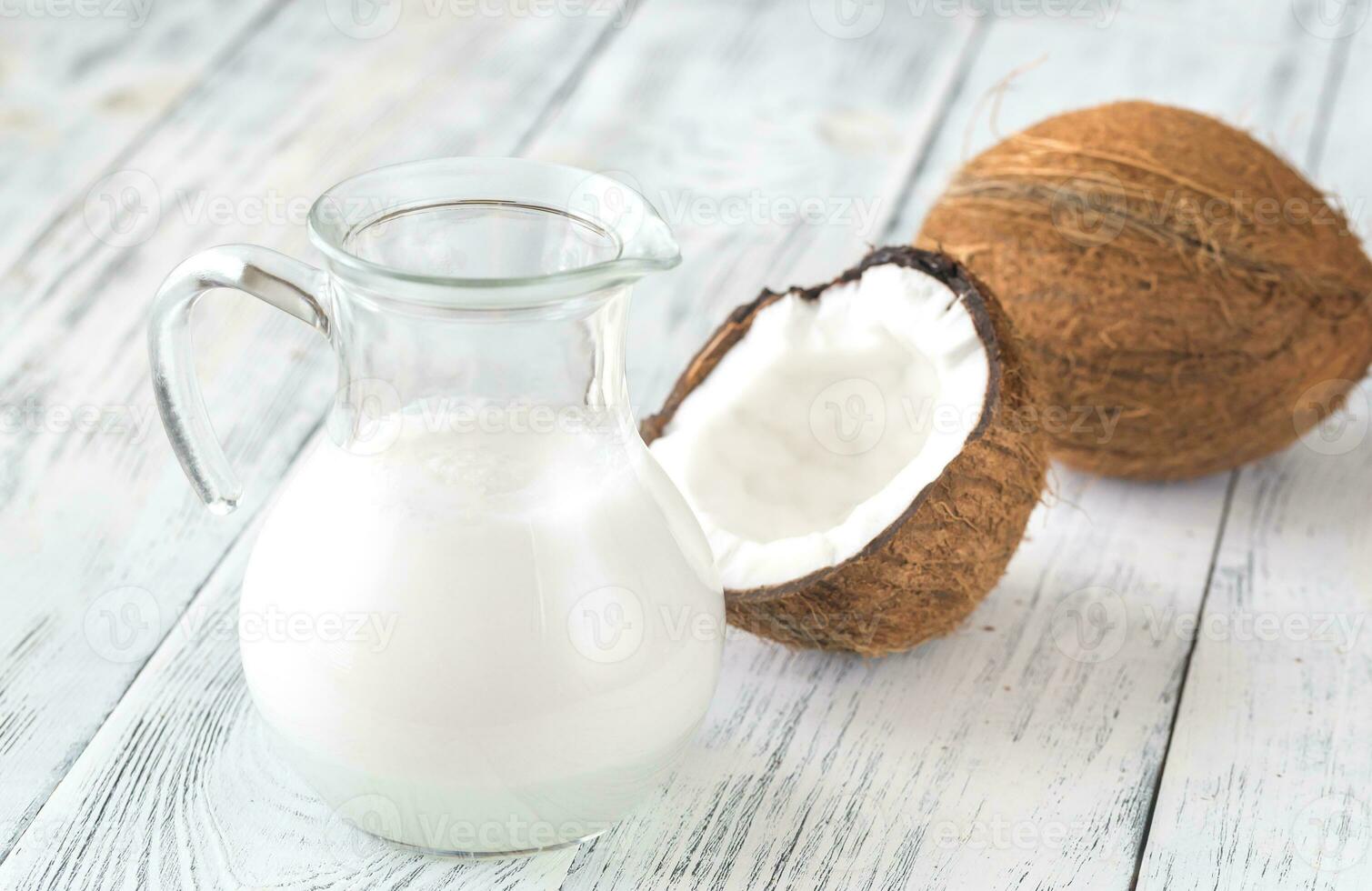 Jug of coconut milk with fresh coconut photo