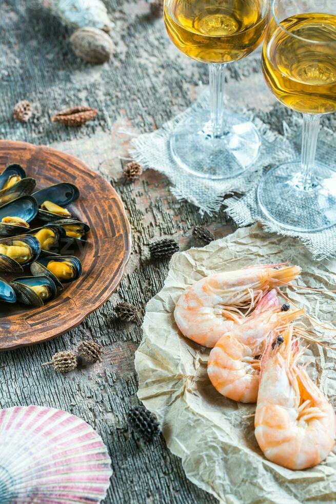 mariscos con dos copas de vino blanco en la mesa de madera foto