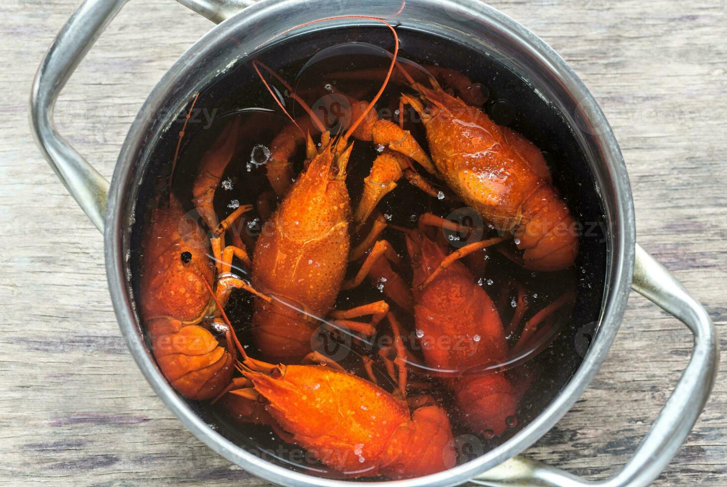 Pot with boiled crayfish on the wooden table photo