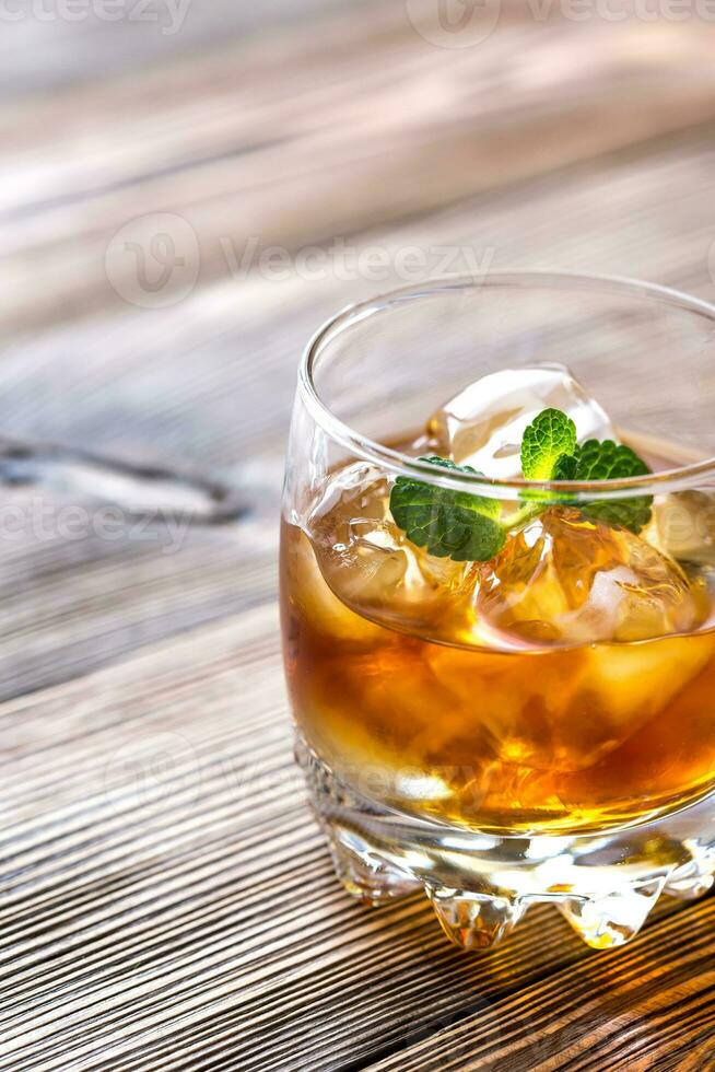 Glass of rum on the wooden background photo
