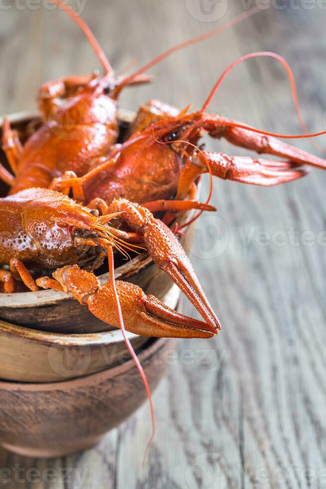 Bowl of boiled crayfish on the wooden table photo