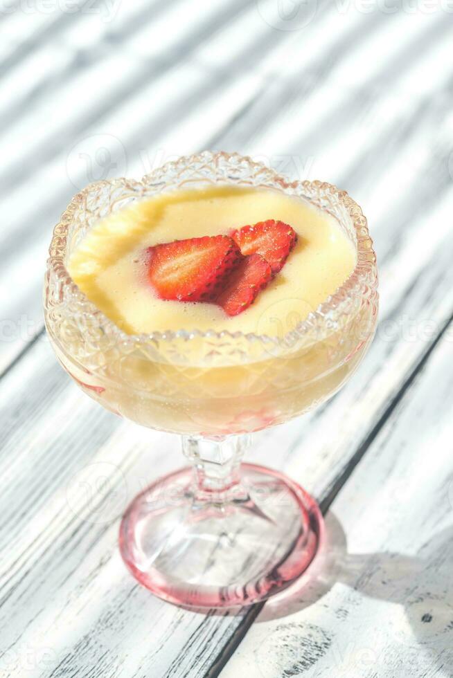 Sabayon with strawberry slices on the wooden background photo